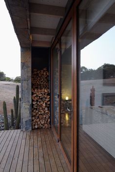 there is a stack of firewood on the outside deck next to an open door