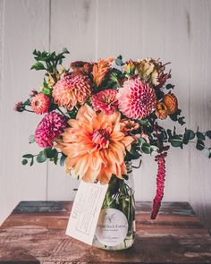 a vase filled with lots of flowers on top of a wooden table next to a sign