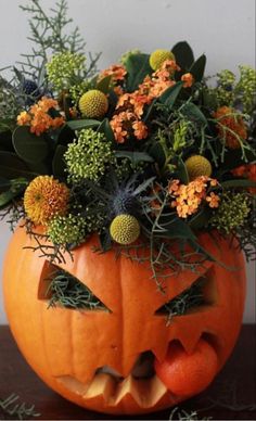 an orange pumpkin decorated with flowers and greenery