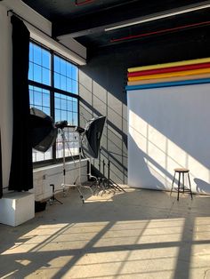 an empty room with large windows and chairs in front of the window is a rainbow - striped wall