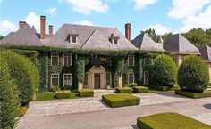 a large house with lots of green plants on the front and side of it, surrounded by hedges