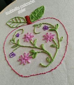 an embroidered apple with leaves and flowers on the inside is shown in pink, purple and green