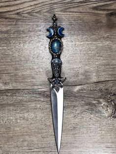 a knife with blue glass beads hanging from it's side on a wooden surface