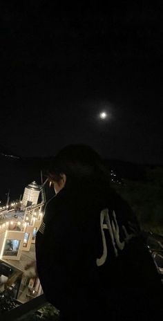 a person standing in front of a building at night with the moon shining over them