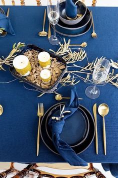 a table set with blue linens and gold place settings for an elegant dinner party