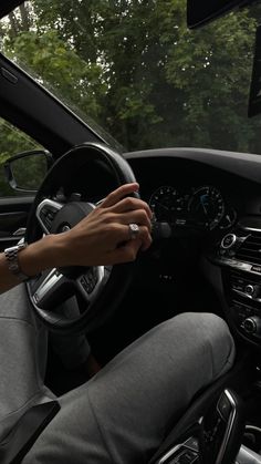 a person driving a car with their hand on the steering wheel and holding onto the dashboard