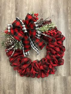 a red and black christmas wreath on a wooden floor