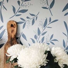 some white flowers and a wooden cutting board on a table with a wallpapered background