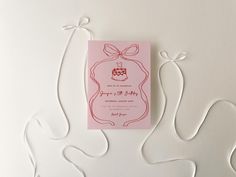 a pink wedding card with a bow on the front and back is surrounded by white string