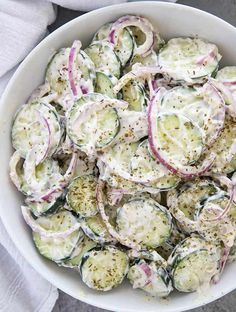 a white bowl filled with cucumber salad on top of a table