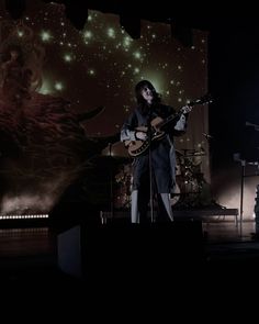 two people on stage playing guitars and singing