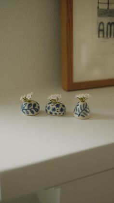 three small blue and white vases sitting on top of a table next to a framed photograph