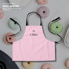 a pink apron with the word choe on it next to donuts and doughnuts