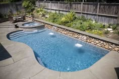 a backyard with a swimming pool surrounded by landscaping