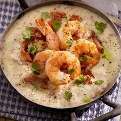 a bowl filled with shrimp and grits on top of a blue towel next to a spoon