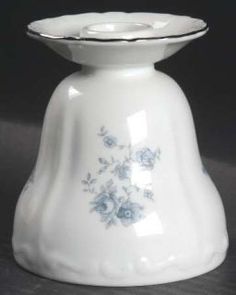 a small white vase with blue flowers on it's side and a black background