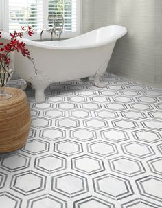 a white bath tub sitting in a bathroom next to a wooden stool with flowers on it