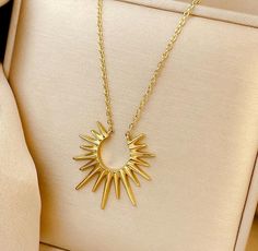 This radiant sunburst necklace is a bold statement piece that will instantly elevate any outfit. Its striking golden design features sharp, sleek rays that fan out around a crescent center, symbolizing power, light, and transformation. The polished finish catches the light beautifully, making it perfect for both day and night wear. Suspended on a delicate gold chain, this necklace adds a modern, sophisticated edge to any look. Whether you're looking to make a statement or add a touch of celestia Necklace For Women Gold, Geometric Pendant Necklace, Golden Design, Half Circle, Geometric Pendant, Choker Necklaces, Chic Accessories, Chain Ring, Gold Pendant Necklace