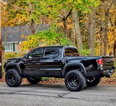 a black truck is parked on the side of the road in front of some trees