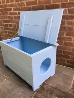 a blue wooden toy chest sitting next to a brick wall