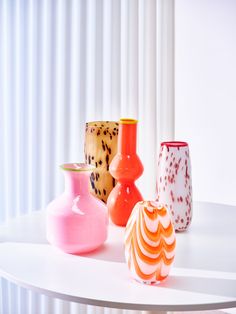 several different colored vases on a white table