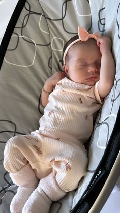 a baby sleeping in a crib wearing a pink bow