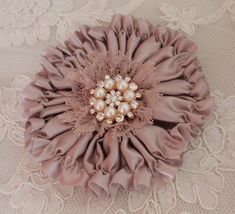 a brooch with pearls on it sitting on a lace tablecloth covered table cloth