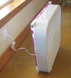 an electronic device sitting on the floor next to a window sill with a cord plugged into it