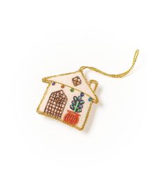 a small house ornament hanging from a gold chain on a white background,