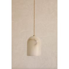 a white light hanging from a gold colored cord on a wall with a beige background