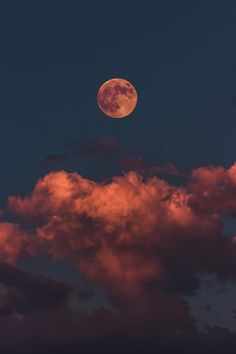 the full moon is shining brightly in the night sky above some pink clouds and dark blue skies