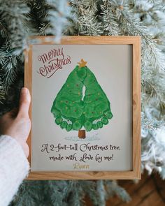 someone holding up a christmas card with a tree on it