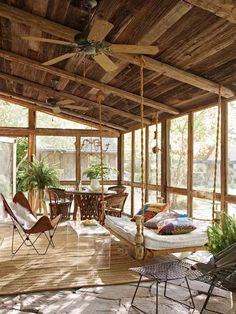 a porch with lots of furniture and plants on the ceiling, along with large windows