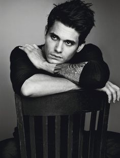 a black and white photo of a man sitting in a chair with his arms crossed