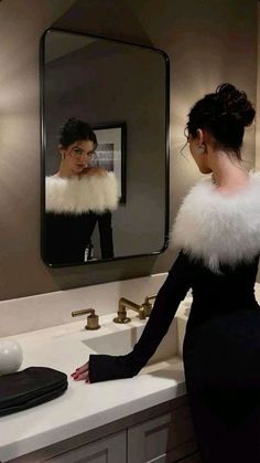 a woman standing in front of a bathroom mirror