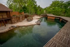 an animal enclosure with water and trees in the background