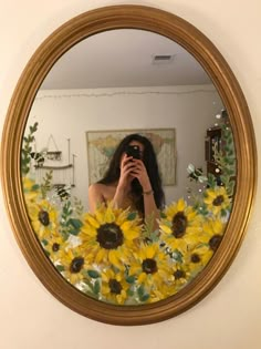 a woman taking a selfie in front of a mirror with sunflowers on it