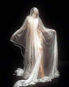 a woman wearing a white veil and dress in the dark