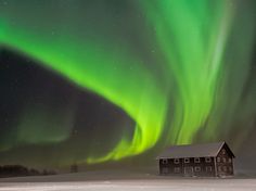 the aurora bore is shining brightly in the sky above a small cabin on snow covered ground