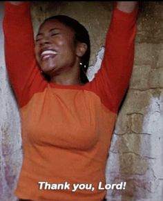 a woman in an orange and black shirt holding her arms up