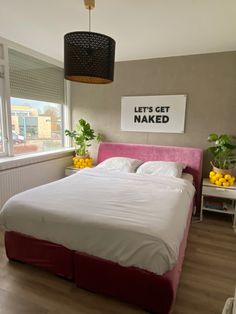 a bed with white sheets and pink headboard in a bedroom next to a window