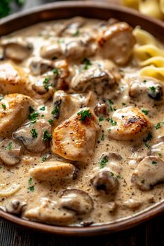 a bowl filled with chicken and mushrooms covered in gravy on top of pasta