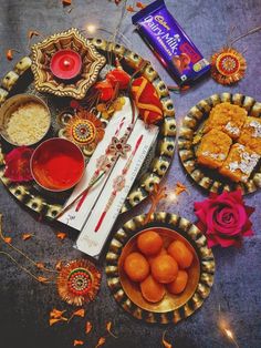 an assortment of food items displayed on decorative trays with candles and flowers around them