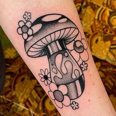 a black and white mushroom tattoo on the right arm, with flowers around it's base