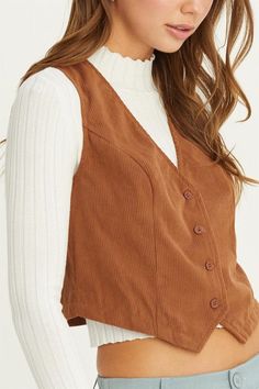 ADD A TOUCH OF SOPHISTICATION TO YOUR WARDROBE WITH THIS V-NECK BUTTONED VEST. CRAFTED FROM A SOFT, RIBBED FABRIC, THIS VEST FEATURES A FLATTERING V-NECKLINE AND A FRONT BUTTON CLOSURE FOR A CLASSIC LOOK. THE TAILORED FIT AND DARTED BODICE ENSURE A FIGURE-HUGGING SILHOUETTE, WHILE THE SLEEVELESS DESIGN MAKES IT PERFECT FOR LAYERING OVER BLOUSES OR UNDER JACKETS. IDEAL FOR BOTH CASUAL AND FORMAL OCCASIONS, THIS VEST CAN BE PAIRED WITH TROUSERS OR SKIRTS FOR A POLISHED ENSEMBLE.model is wearing a Corduroy Vest, Tank Top Crop Top, Bardot Top, Hugging Silhouette, Blouse Tank Top, Hoodie Cardigan, Flannel Tops, School Looks, Graphic Tops