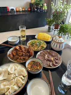 a black table topped with lots of plates and bowls filled with different types of food