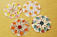 three paper flowers sitting on top of a wooden table