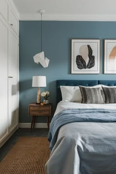 a bedroom with blue walls and pictures on the wall above the bed, along with two nightstands