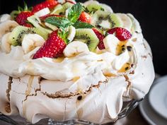 there is a cake with fruit on top and whipped cream in the middle, topped with sliced kiwis