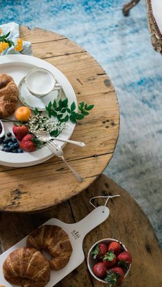 two plates with croissants, strawberries and other food items on them